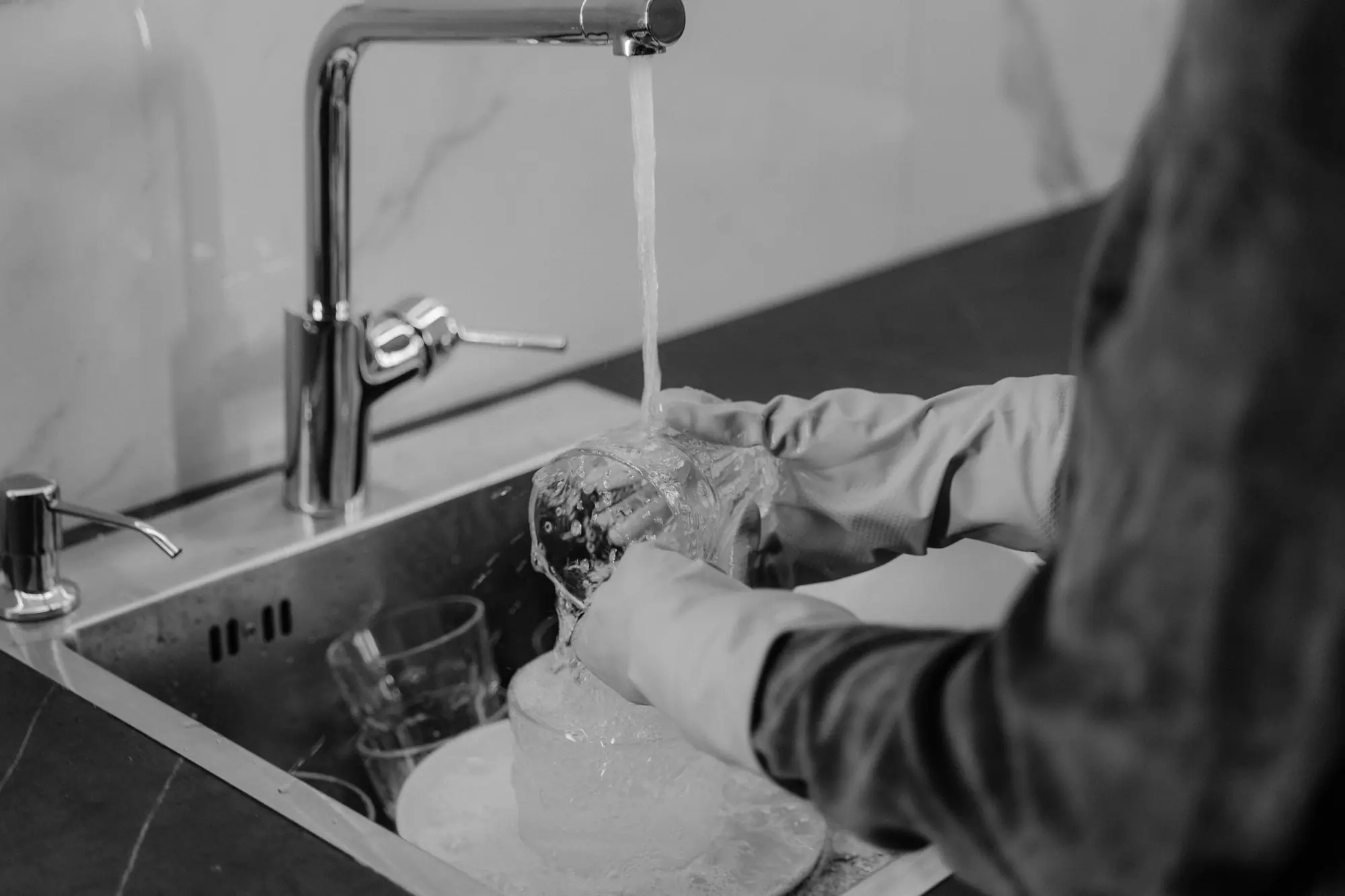 Gloved hands washing glassware
